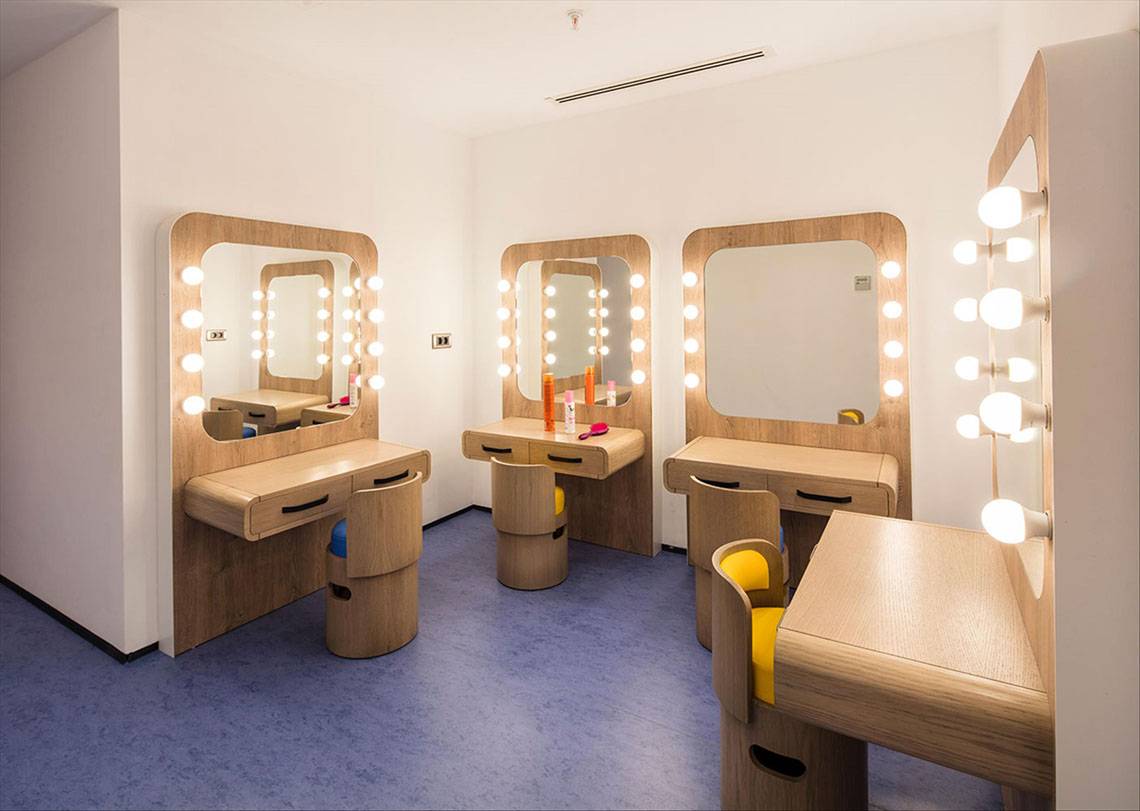 Friseursalon mit mehreren Holzarbeitsplätzen, Spiegeln und Beleuchtung.