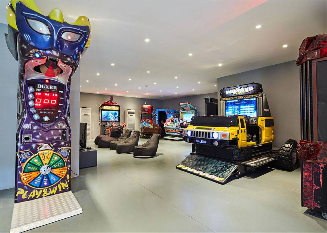 Spielzimmer im Maxx Royal Kemer Resort mit Arcade-Spielen, Sitzsäcken und einer bunten Spielhalle.