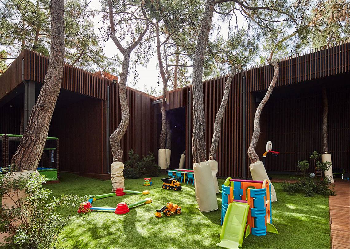 Kinderspielplatz im Maxx Royal Kemer Resort mit Bäumen und Spielzeug.