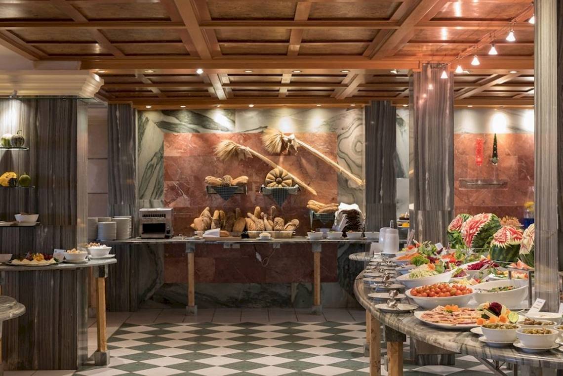 Buffetbereich im Aquila Rithymna Beach Hotel mit verschiedenen Speisen und einem braunen Hintergrund.