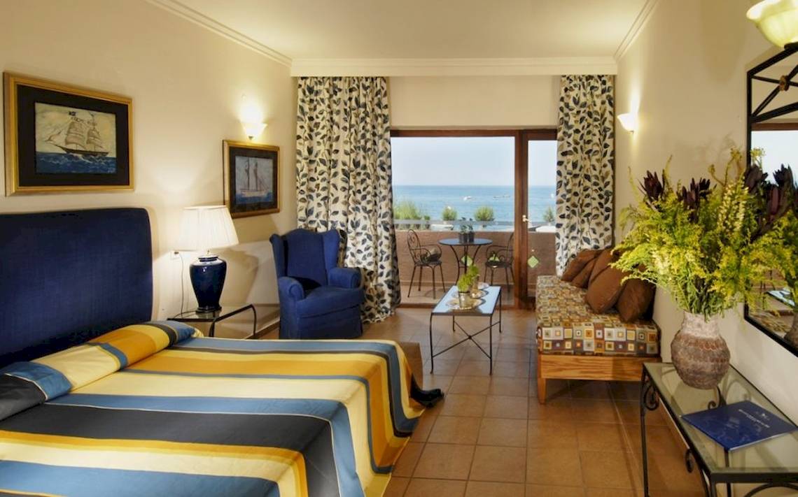 Aquila Rithymna Beach Hotel Zimmer mit Balkon und Meerblick, mit Bett, Sofa, Tisch, Stühlen und Dekoration.