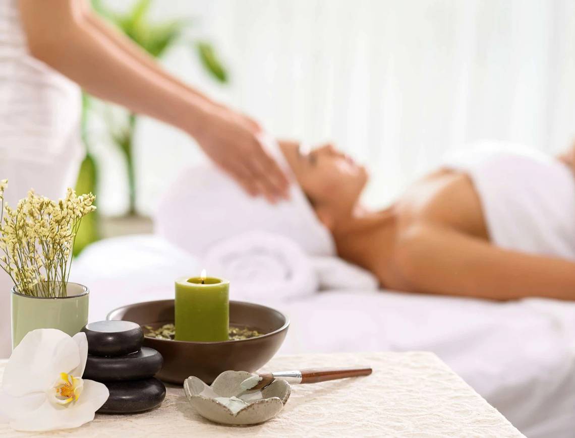 Spa-Behandlung im Minos Imperial Beach Resort mit Kerze und Blumen.
