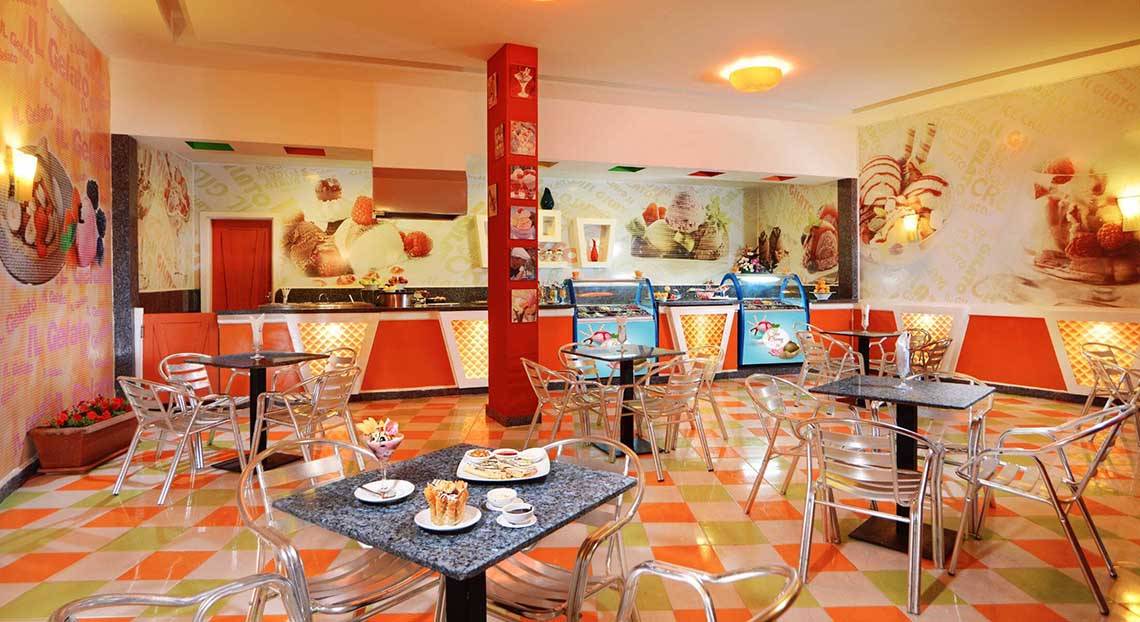 Innenbereich des Restaurants im Pickalbatros Jungle Aqua Park Resort mit bunten Fliesen, Tischen und Stühlen sowie Eiscreme-Wandmalereien.