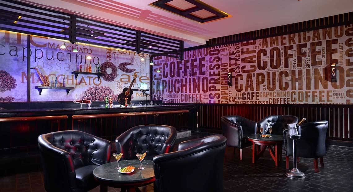 Die Bar des Pickalbatros Jungle Aqua Park Resorts mit schwarzer Einrichtung und einer Wand voller Kaffee-Wortkunst.