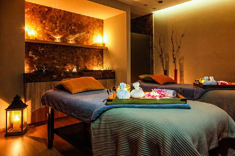 Massage-Behandlungsraum im Crystal Springs Beach Hotel mit zwei Betten, Kerzen und Blumen auf einem Tablett.