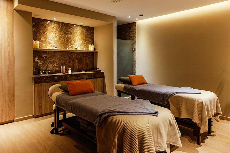 Massage-Lounge im Crystal Springs Beach Hotel mit zwei Massagebetten und Holzmöbeln.