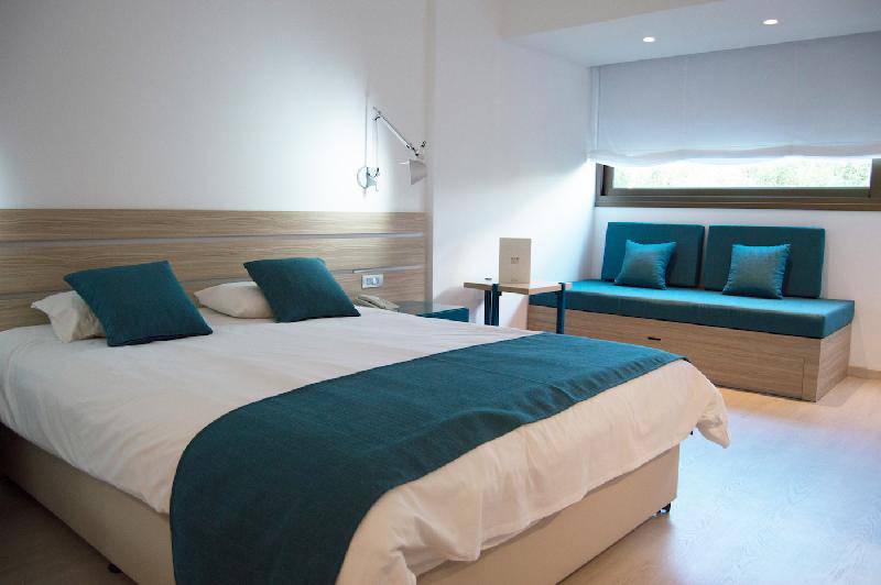 Doppelbett in einem Zimmer im Crystal Springs Beach Hotel mit blauen Kissen und einer Bank.