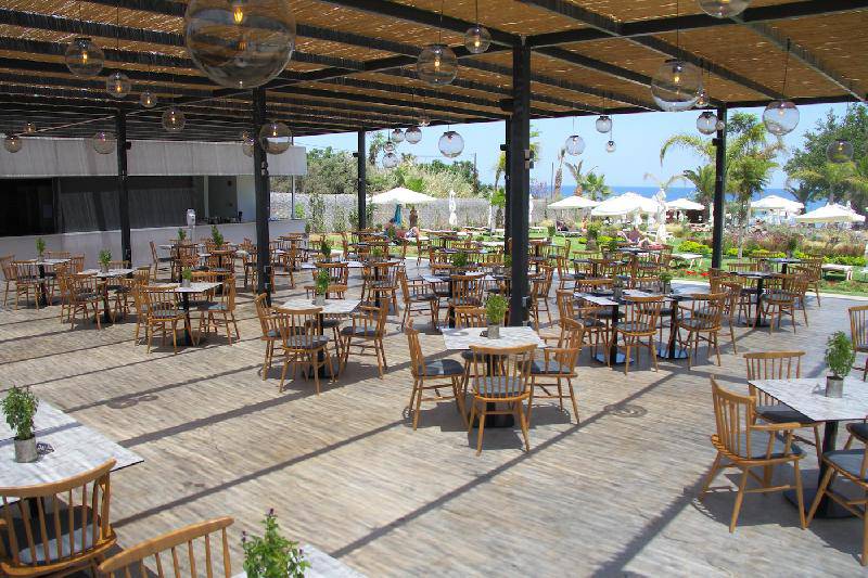 Terrasse im Crystal Springs Beach Hotel mit vielen Tischen und Stühlen.