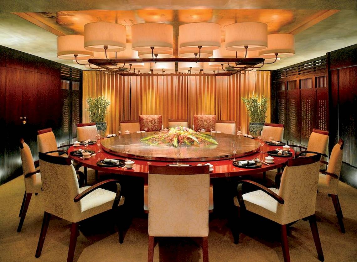 Esszimmer im Al Bustan Palace, A Ritz Carlton Hotel mit einem runden Tisch und Stühlen.