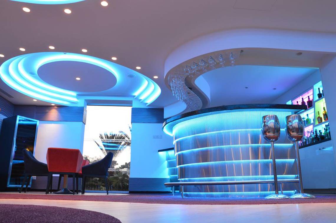Innenansicht der Bar im Vassos Nissi Plage Hotel mit blauen Beleuchtungselementen und modernen Möbeln.