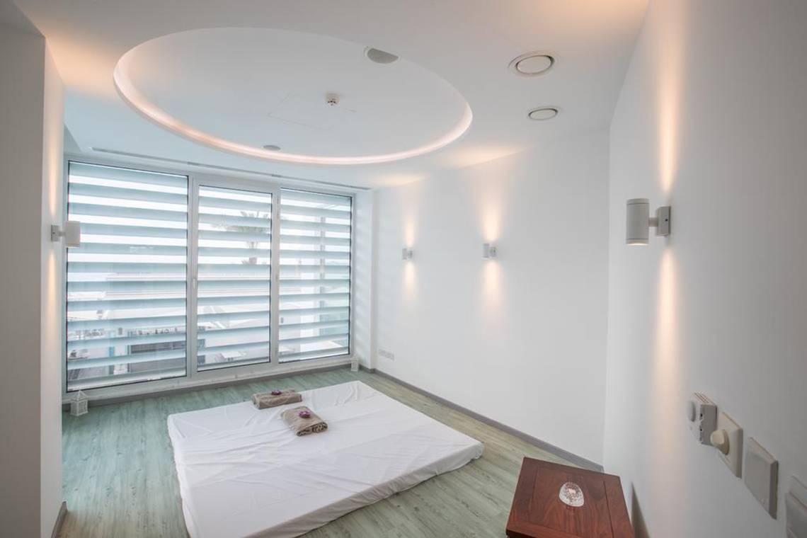 Innenansicht eines Zimmers im Vassos Nissi Plage Hotel mit einem Bett und großen Fenstern.