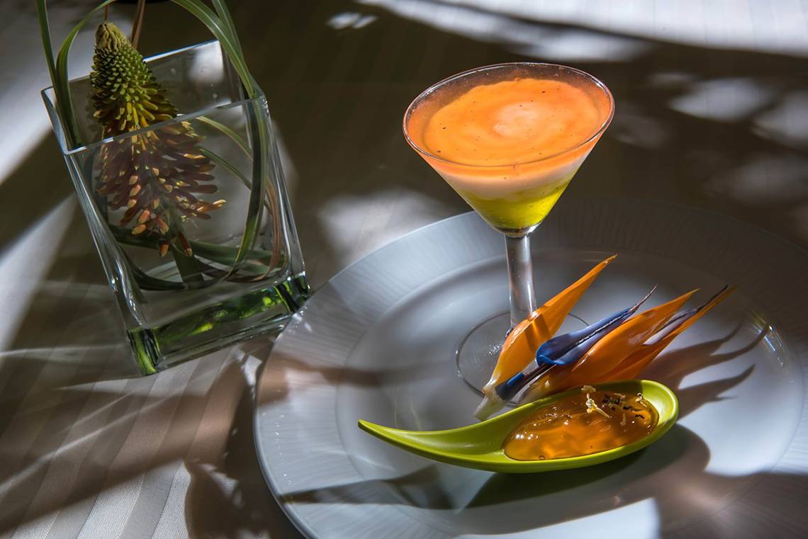Ein Cocktailglas mit einem farbenfrohen Getränk auf einem weißen Teller im Blue Bay Resort.