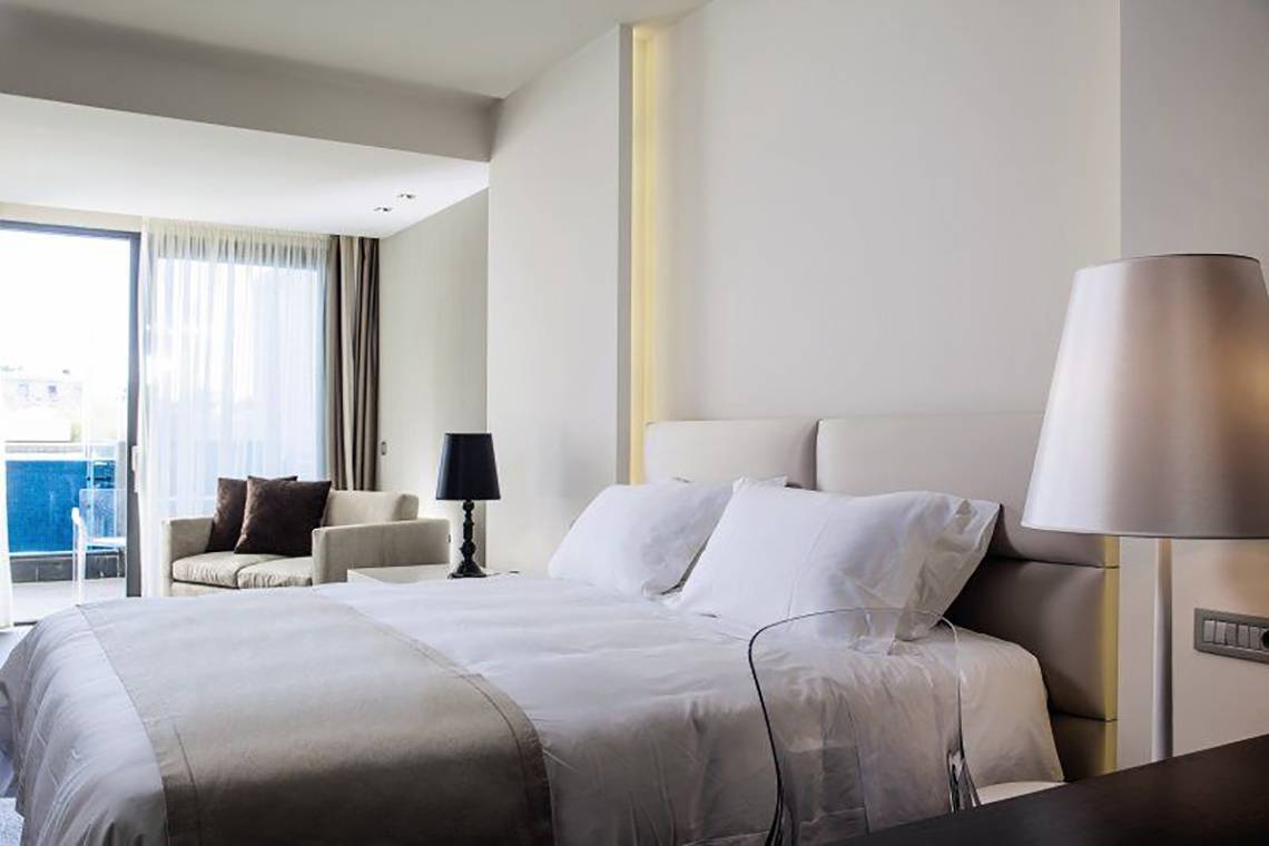 Schlafzimmer im Aqua Blu Boutique Hotel & Spa mit Doppelbett, Sesseln und Glasfenstern.