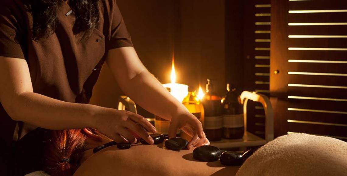 Massage im Aqua Blu Boutique Hotel & Spa mit Kerzenlicht und steinernen Massagewerkzeugen.