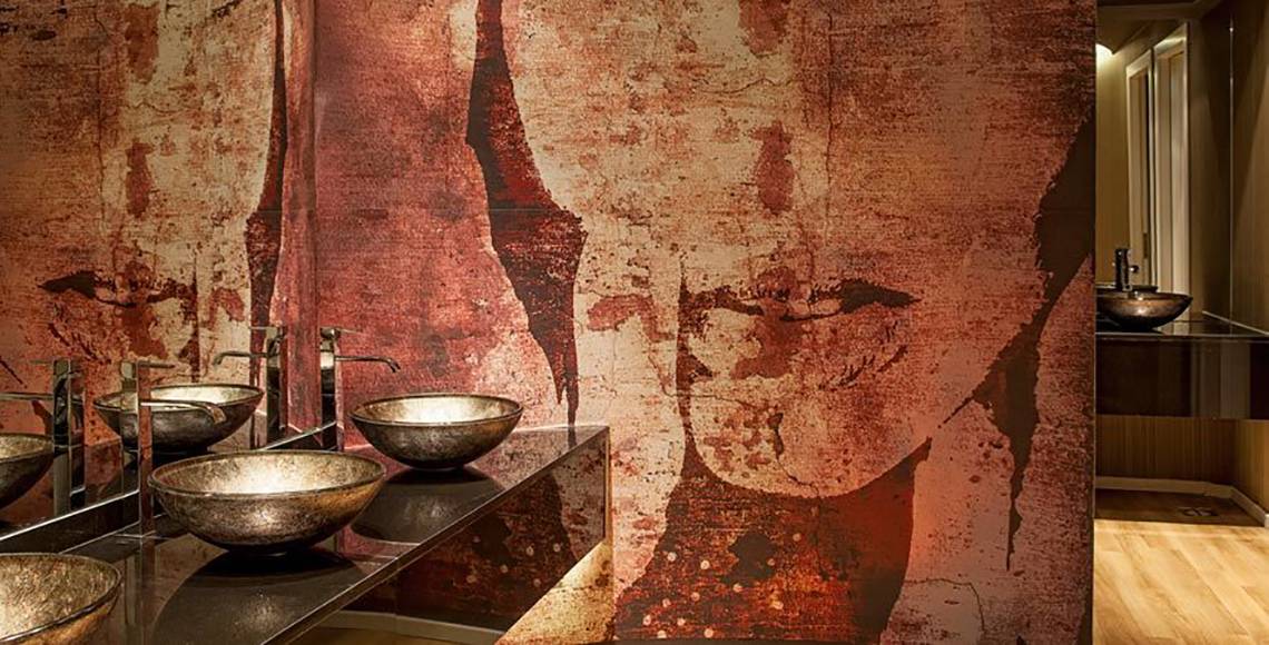Badezimmer im Aqua Blu Boutique Hotel & Spa mit kupferfarbenen Waschbecken und einer Wandverkleidung aus oxidiertem Kupfer.