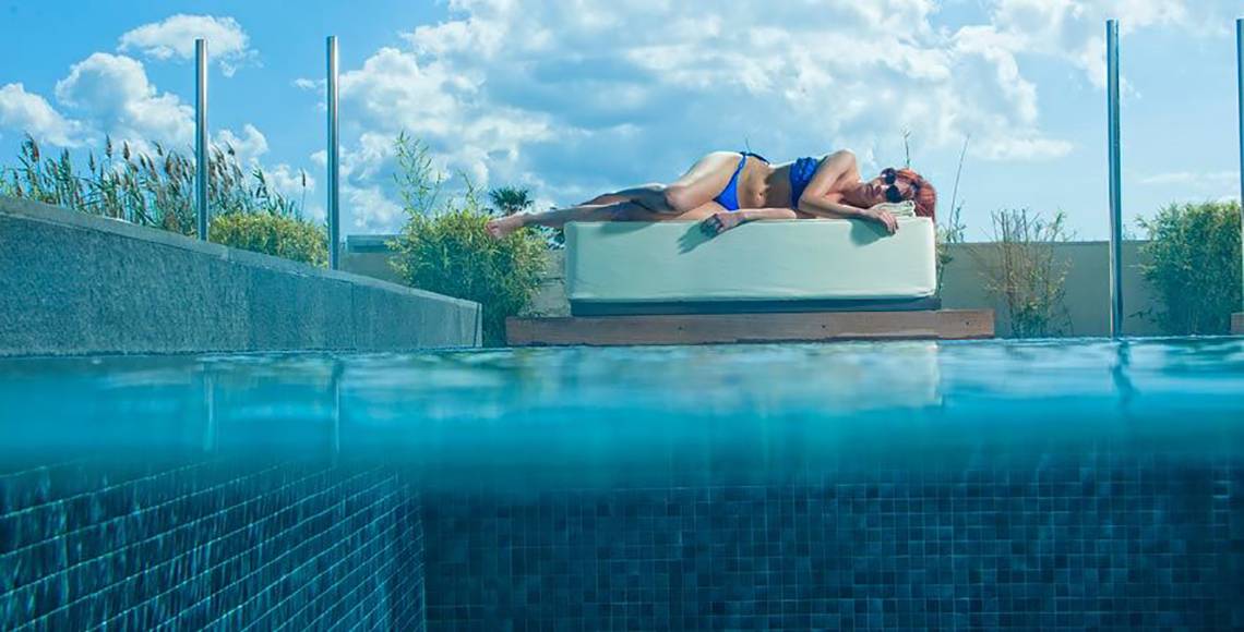 Eine Frau liegt entspannt auf einer Liege im Pool des Aqua Blu Boutique Hotel & Spa.