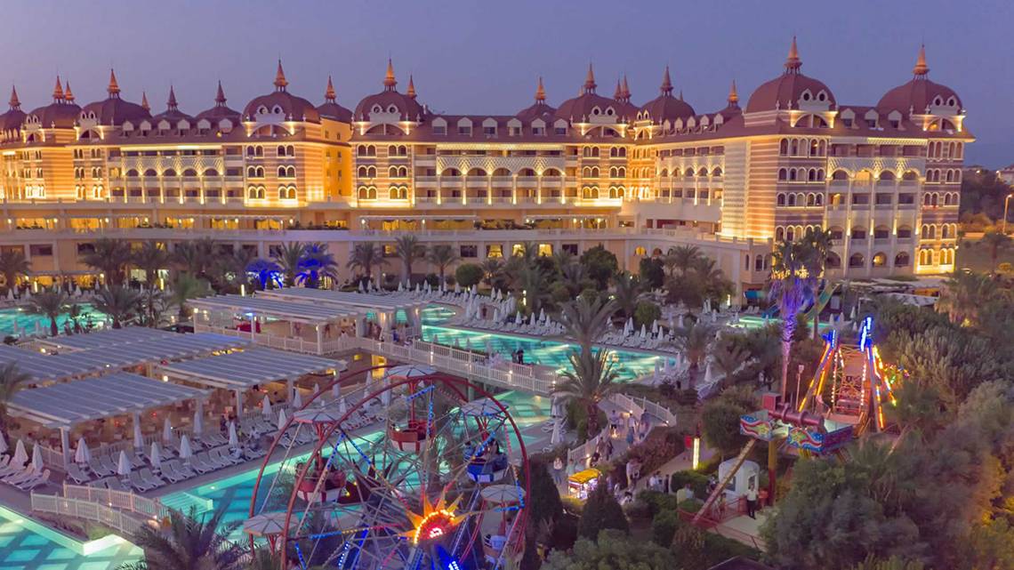 Luftaufnahme des Royal Alhambra Palace Resorts mit beleuchtetem Gebäude, Swimmingpool und Vergnügungspark.