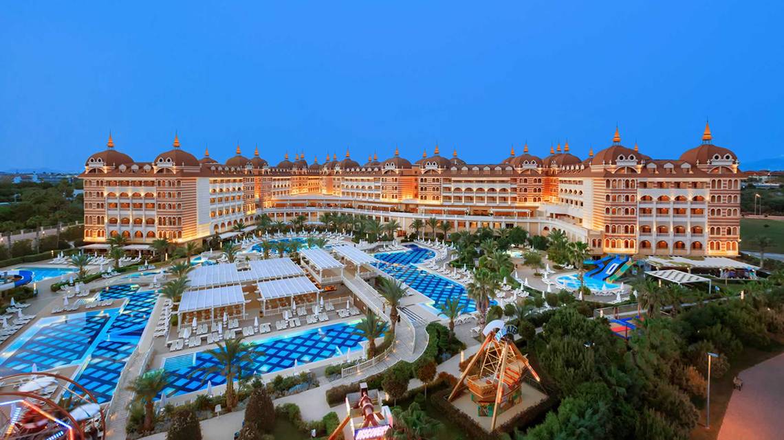 Außenansicht des Royal Alhambra Palace Hotels bei Nacht mit beleuchteten Gebäuden und Pools.