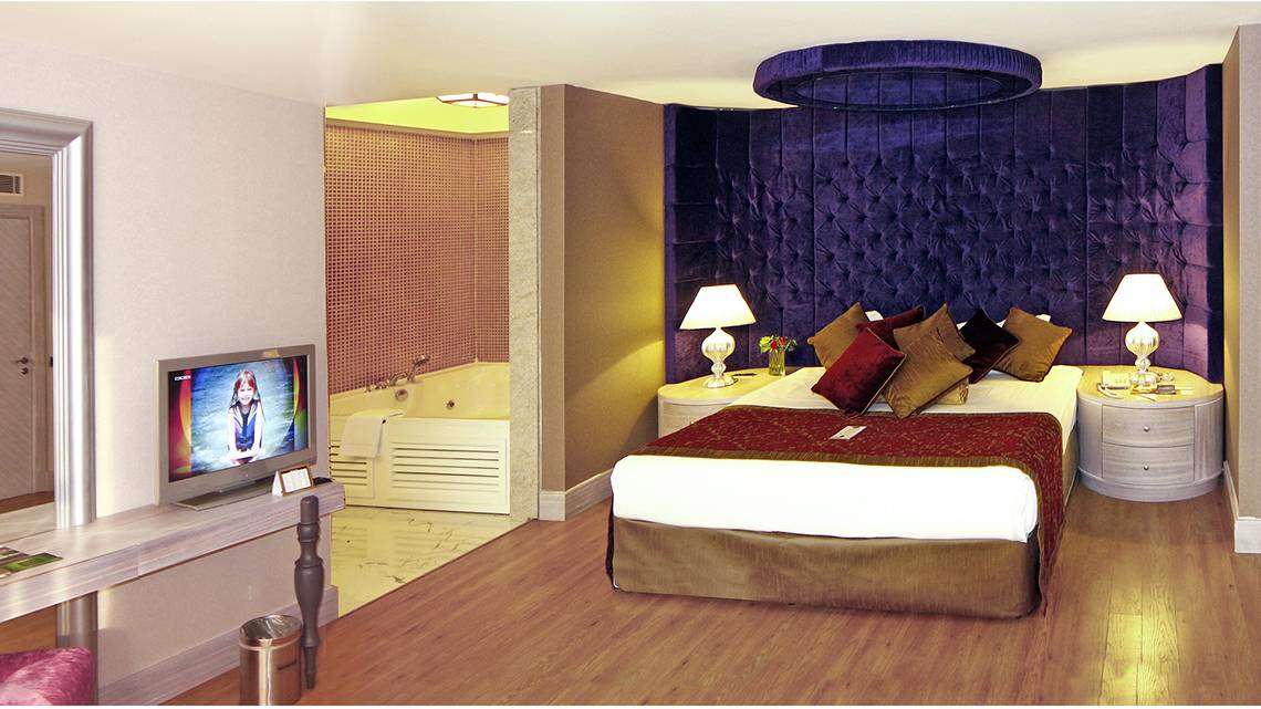 Ein elegantes Hotelzimmer mit einem Bett, Fernseher, Nachttischen und einem Whirlpool.