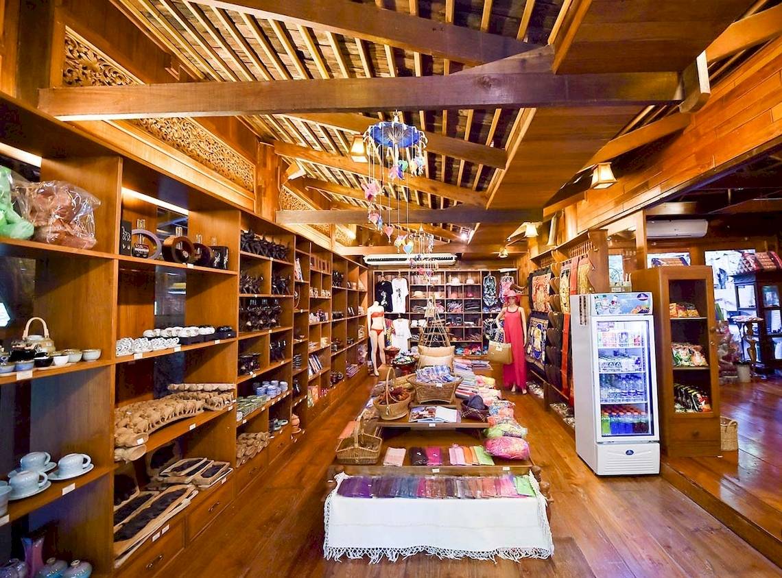 Innenansicht des Santhiya Koh Phangan Resort & Spa Shops mit Holzboden und Regalen voller Produkte.