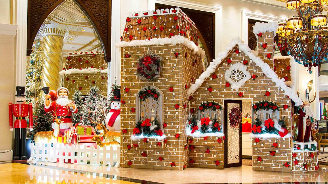 Ein Lebkuchenhaus in der Lobby des Jumeirah Zabeel Saray, geschmückt mit roten Blumen und Weihnachtsdekoration.