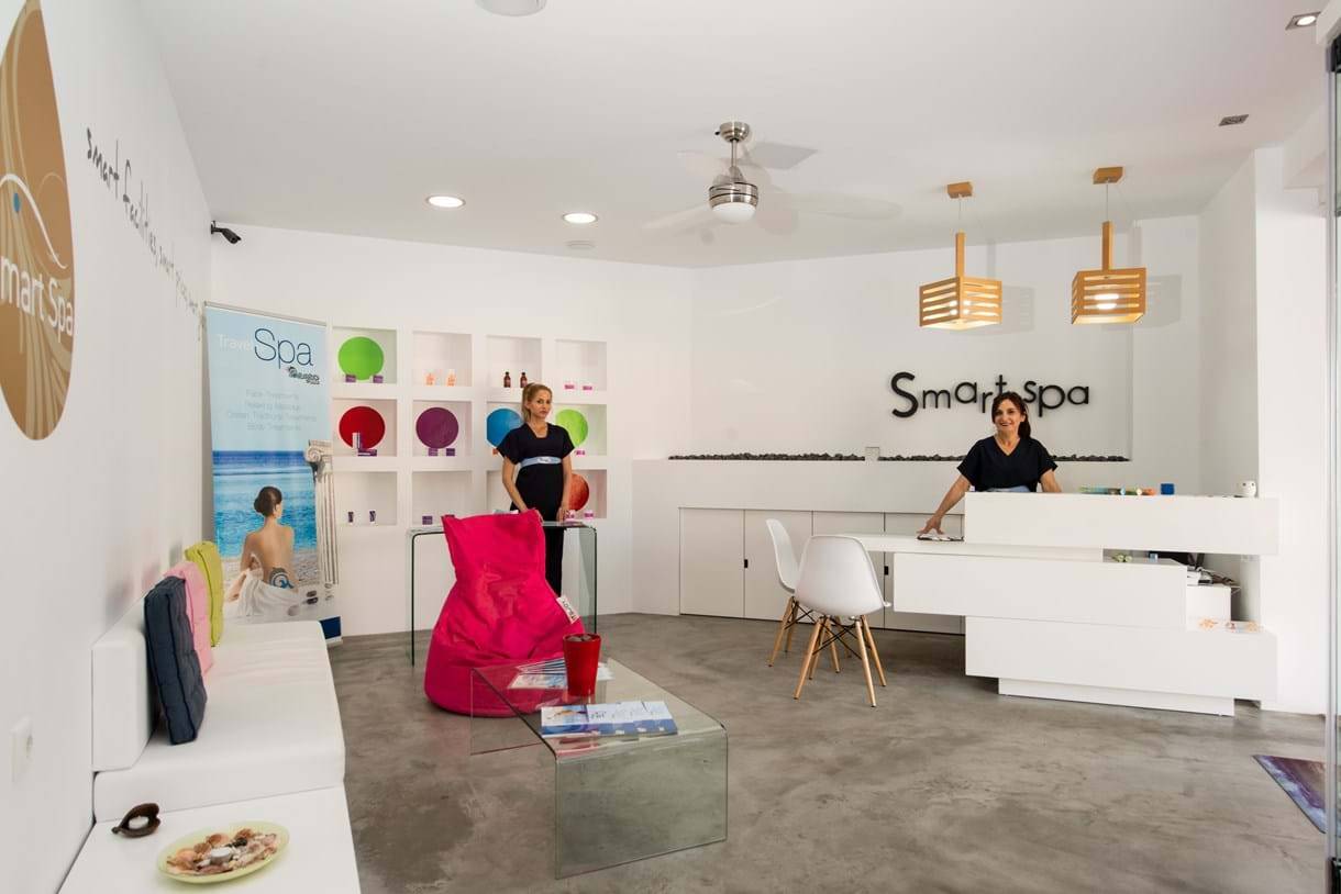 Smart Spa im Fodele Beach & Water Park Holiday Resort mit zwei Frauen an der Rezeption und einer Frau auf einem Werbeplakat.