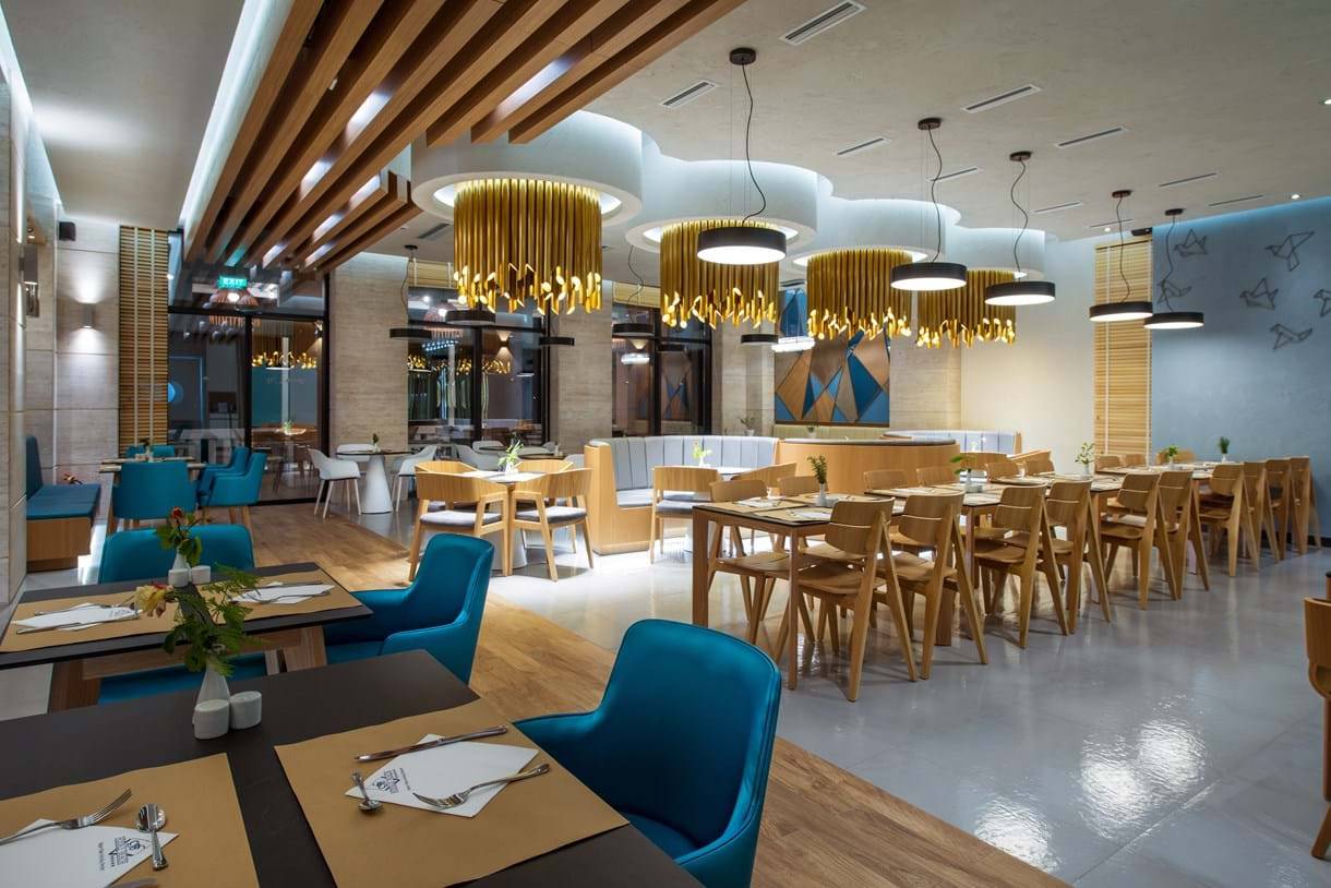 Innenansicht des Restaurants im Fodele Beach & Water Park Holiday Resort mit blauen Stühlen und Holztischen.