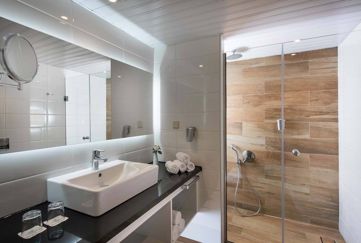 Badezimmer im Fodele Beach & Water Park Holiday Resort mit ebenerdiger Dusche, Waschbecken und Spiegel.