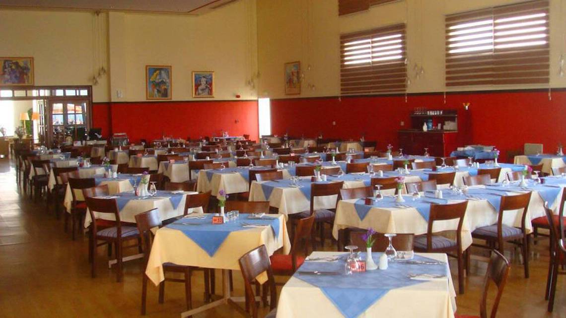 Restaurant des Aktea Beach Village Hotels mit vielen blau-weiß gedeckten Tischen und Stühlen.
