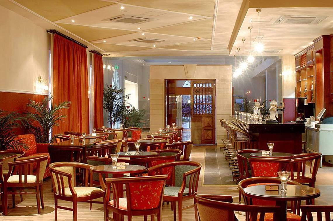 Innenansicht des Restaurants im Aktea Beach Village Hotel mit runden Tischen und Stühlen.