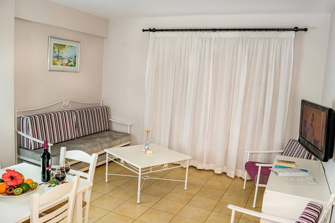 Wohnbereich im Aktea Beach Village Hotel mit Couch, Tisch, Fernseher und Obstteller