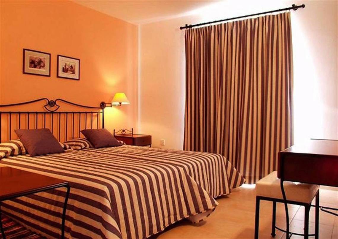 Doppelzimmer im Aktea Beach Village Hotel mit zwei Betten, Tisch, Stuhl, Lampe und Wanddekoration.
