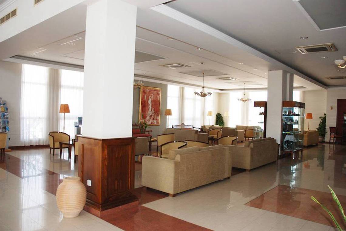 Aktea Beach Village Hotellobby mit Sofas, Lampen und Gemälden an der Wand.