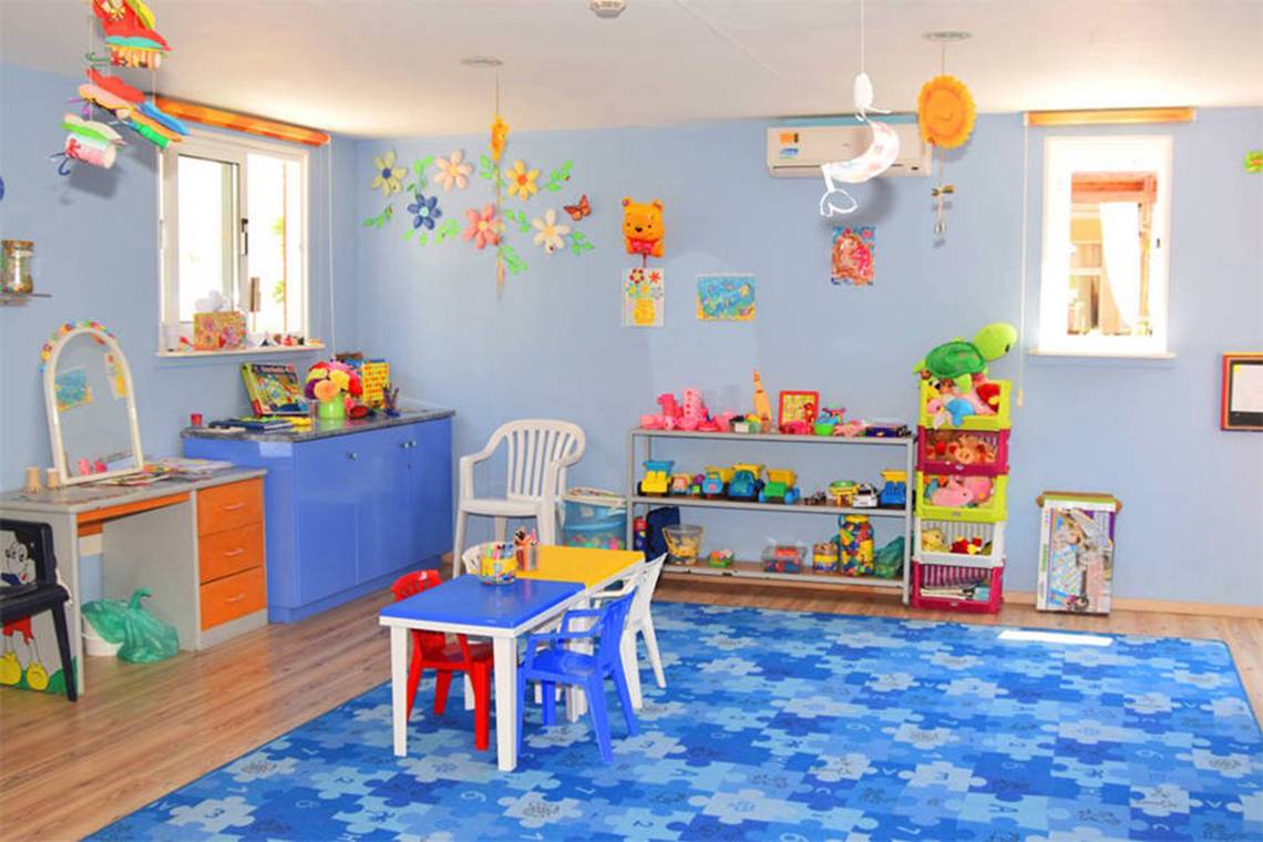 Kinderzimmer im Aktea Beach Village Hotel mit blauen Wandfarben, Spielzeug und Möbeln.