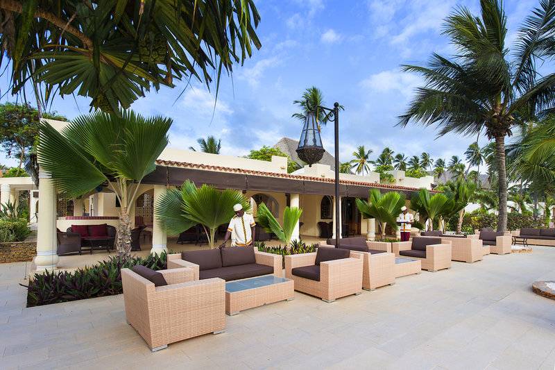 Loungebereich vor dem Bahari Zanzibar Hotel mit braunen Möbeln und Palmen.