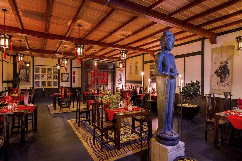 Innenansicht des Bahari Zanzibar Restaurants mit Buddha-Statue, gedeckten Tischen und traditioneller Dekoration.