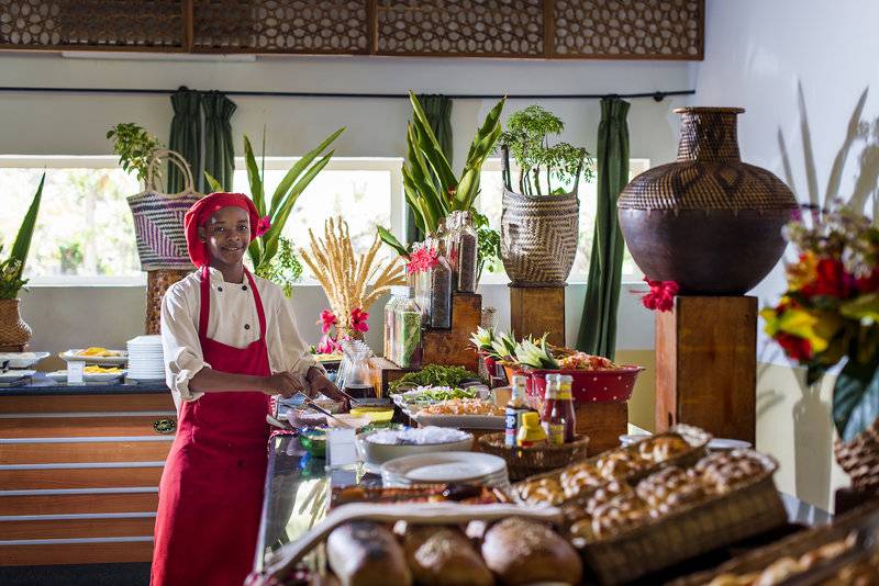 Eine Mitarbeiterin des Bahari Zanzibar Hotels bereitet das Frühstücksbuffet vor.