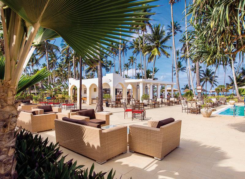 Außenbereich des Bahari Zanzibar Hotels mit Lounge-Sesseln, Tischen und Palmen.