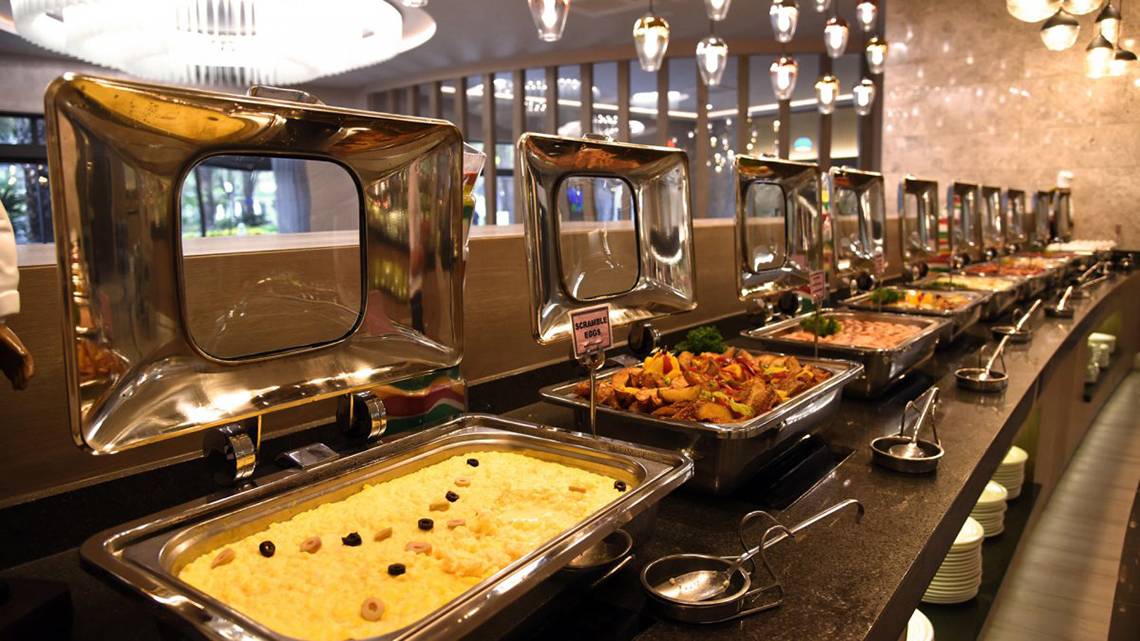 Buffet-Tisch im Royal Wings Hotel mit verschiedenen Gerichten in silbernen Aufwärmschalen.