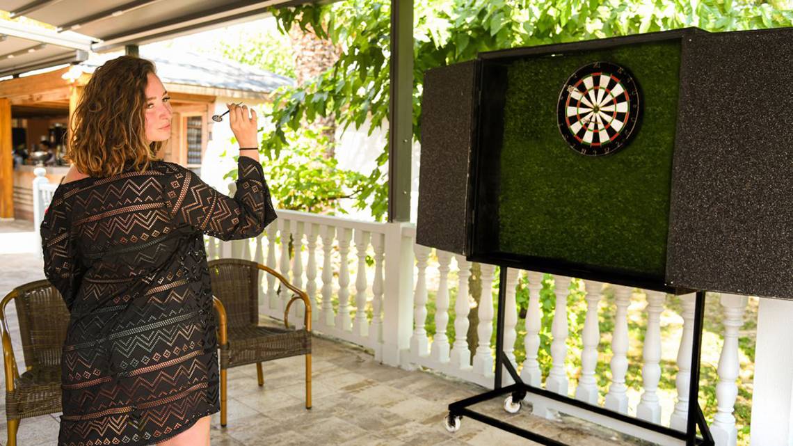 Eine Frau wirft ein Dart auf eine Zielscheibe im Freien im Hotel Royal Wings.