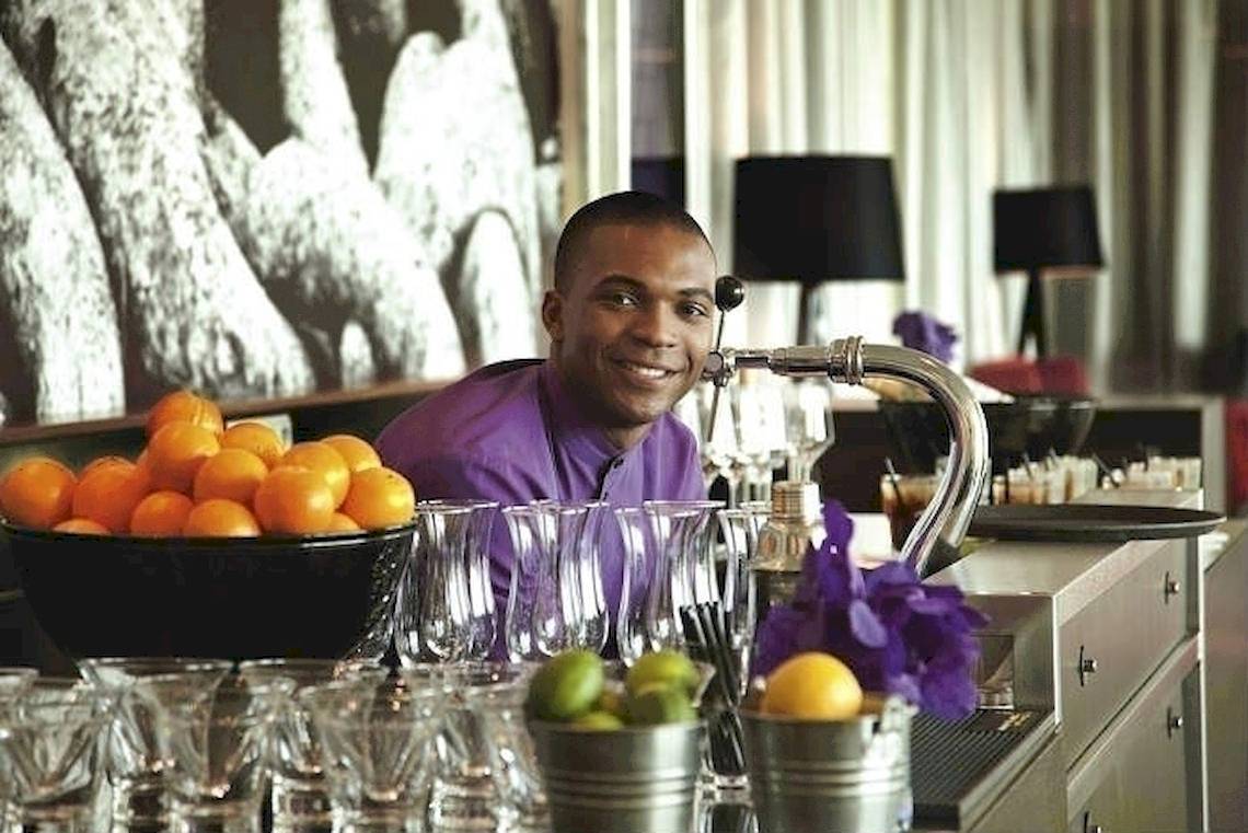 Ein Mann im lila Hemd hinter der Bar des Mövenpick Amsterdam City Centre