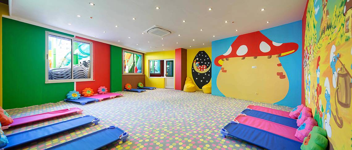 Kinderzimmer im Crystal Sunset Luxury Resort & Spa mit bunten Wänden, runden Möbeln und einem großen Wandbild.