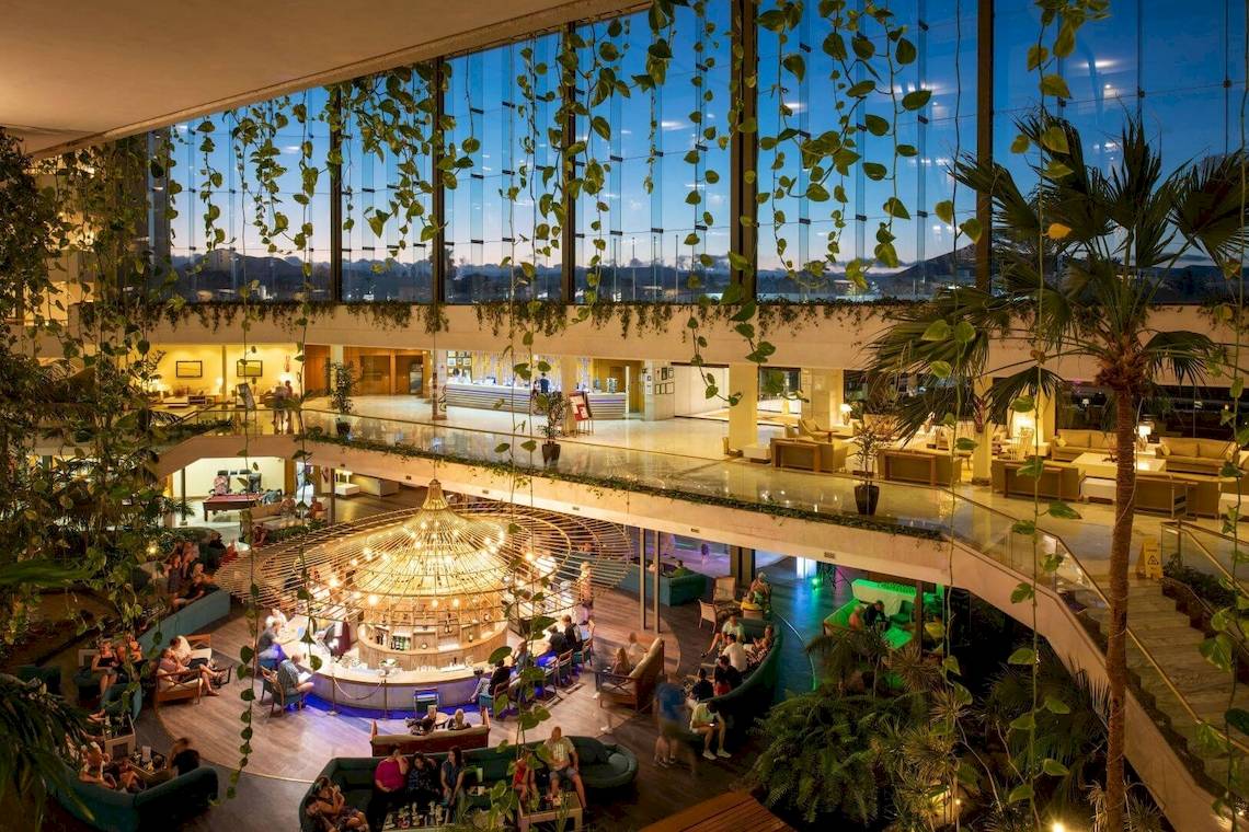 Innenansicht des Grand Teguise Playa Hotels mit Atrium, Sitzbereichen und beleuchteter Bar.