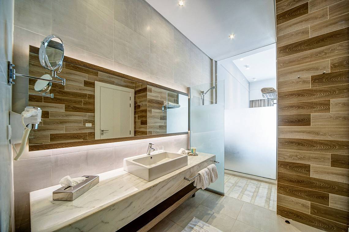 Badezimmer im Ancient Sands Golf Resort mit weißem Waschbecken und Holzverkleidungen.