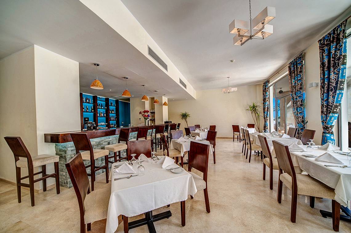 Innenansicht des Restaurants im Ancient Sands Golf Resort mit Tisch und Barbereich