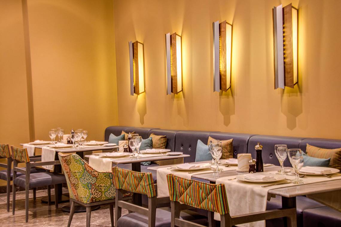 Innenbereich des Ancient Sands Golf Resort Restaurants mit blauen Sofas und illuminierten Wandleuchten.