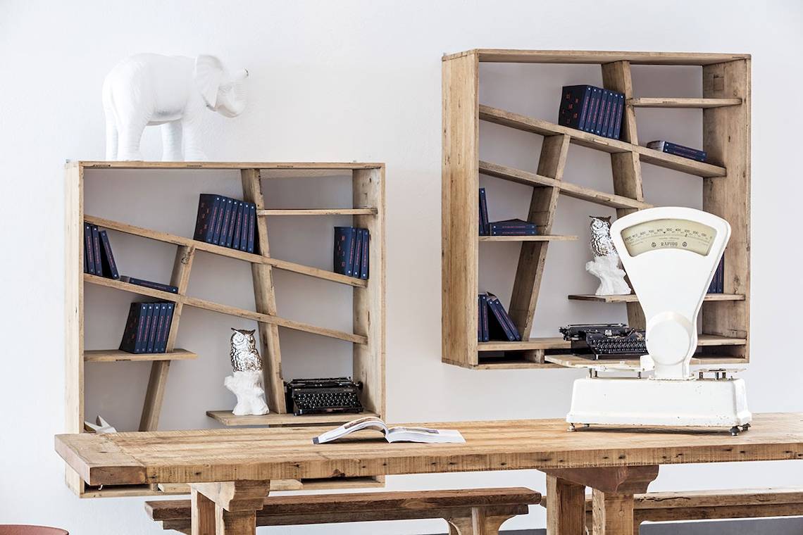 Zwei Holzregale mit Büchern und Dekorationen in einem Zimmer, ein Regal hat eine Figur eines Elefanten obenauf.
