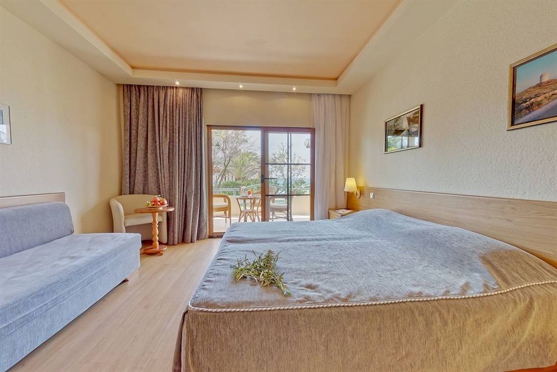 Schlafzimmer im Possidi Holidays Resort & Suites mit Doppelbett, Sofa und Balkon