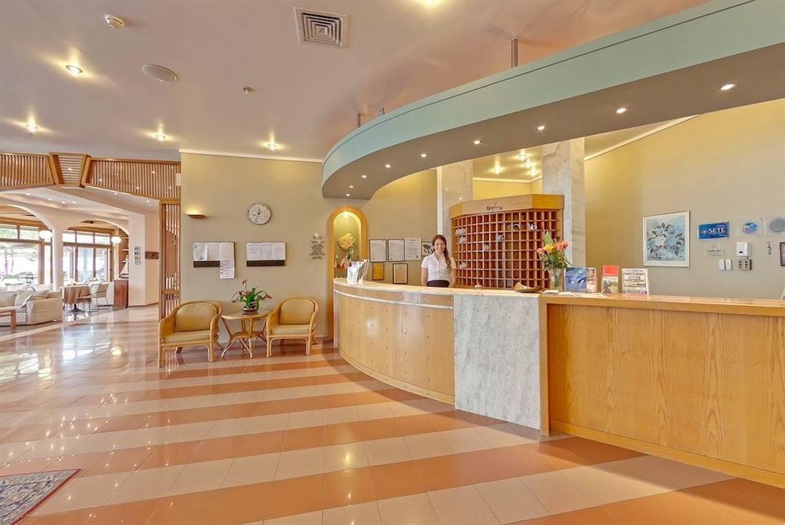 Empfangsbereich des Possidi Holidays Resort & Suites mit Rezeptionstresen, sitzender Rezeptionistin und Einrichtung.