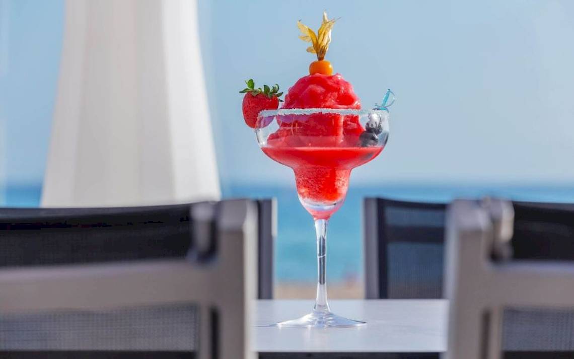 Roter Cocktail in einem Glas mit Blick auf den Strand und das Meer